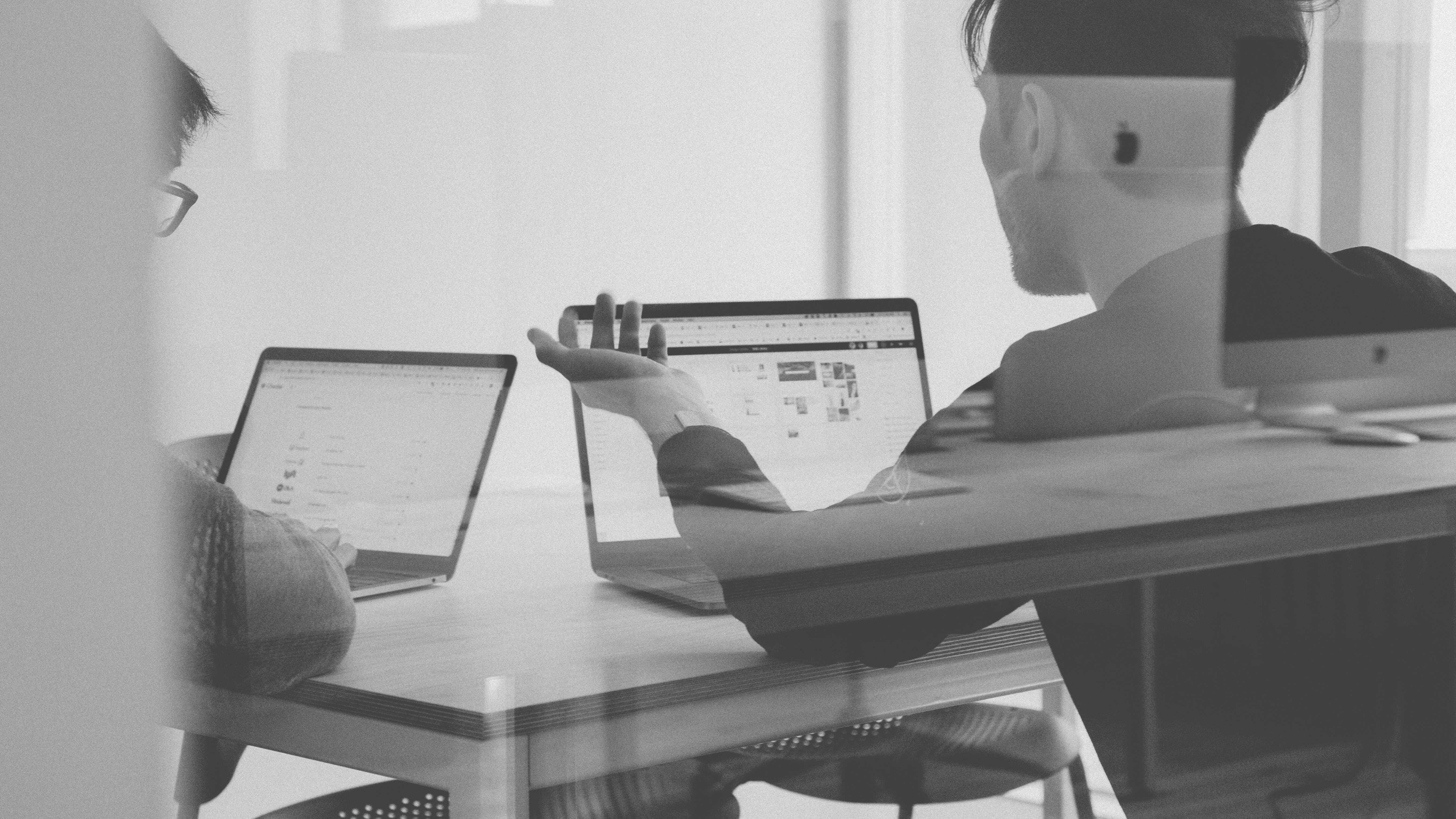 Zwei Personen besprechen Markenstrategien am Laptop in einem modernen Büro